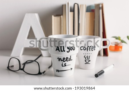 Hipster cup of coffee on a books library./ Two white coffee mug with diy decoration. 