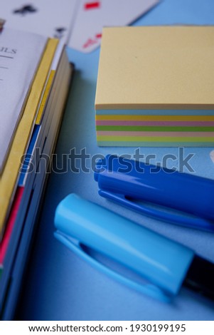 The photo is a photo of stationery in the form of books, pens, and sticky notes taken from a close distance