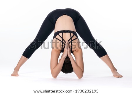 Beautiful sporty woman doing advanced yoga practice on white background. Feet spread out intense stretch pose.