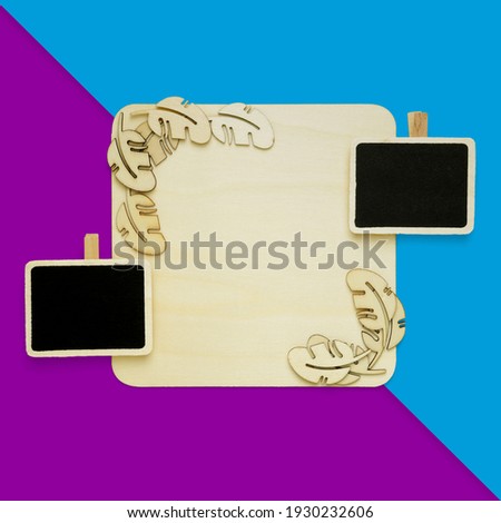 blank square wooden board with wooden leaves shapes decor and black boards on blue and purple color blocks background with copy space. top or flat lay view. suitable for message or announcement design