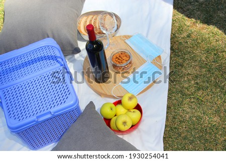 close up and zenith view of pandemic picnic. basket with wine, food, fruit, seeds and protective masks for clinical use