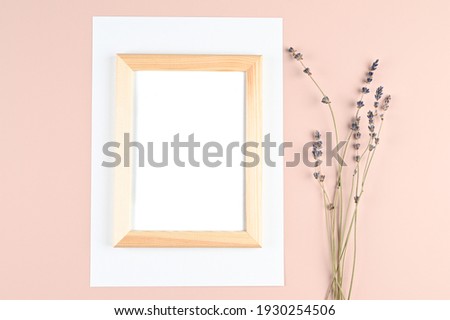 Wooden photo frame with white blank card and lavender flowers on pastel pink background. Mock up poster frame. Stylish template. High quality photo
