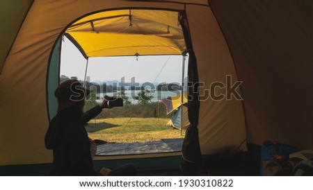 A female Asian tourist sits in a tent taking photos of the beaut