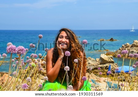 Beautiful portrait picture of a young model on La Maddalena island, Sardegna Italy in the fields with a beach background in the Mediterranean Sea.