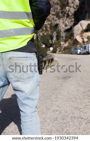 A road worker with a walkie talkie and a reflective vest while holding a stop sign on a mountain road in Majorca