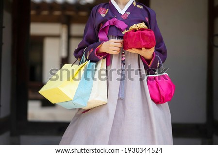Woman in Korean traditional clothes holding traditional package and shopping bags
 Royalty-Free Stock Photo #1930344524