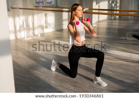 beautiful young woman with a slim figure goes in for sports with dumbbells 