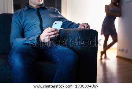 Jealous woman and cheating man with a phone. Infidelity, jealousy and betrayal. Cheater husband texting with mistress and secret lover. Suspicious wife peeking and spying. Unfaithful sneaky boyfriend. Royalty-Free Stock Photo #1930394069