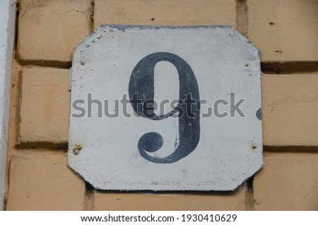 A sign on a wall with the number nine-9