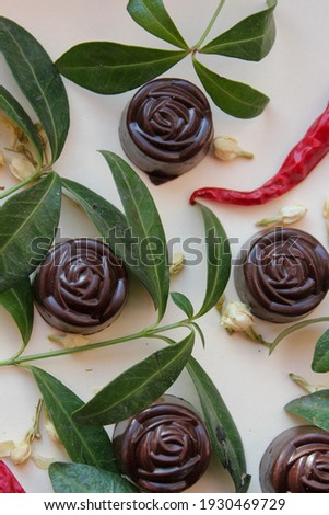 the composition of capsicum, chocolate candies in the form of flowers in green on a light background 