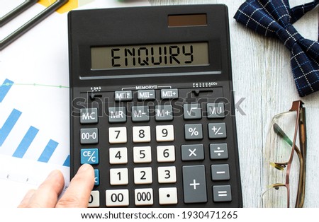 A calculator labeled ENQUIRY lies on financial documents in the office.