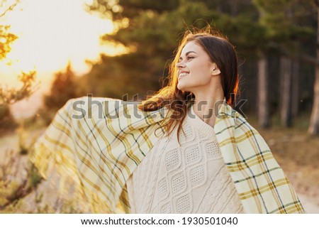 happy woman tourist in a warm sweater in the summer in nature near the forest
