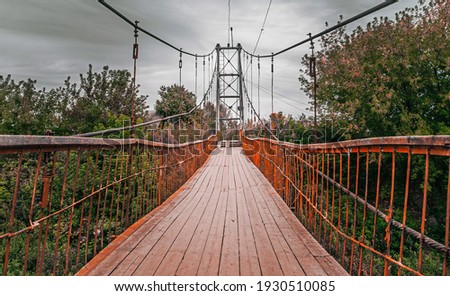 Old iron suspension bridge over a rive. Pedestrian bridge in Kungur, Perm Krai, Russia