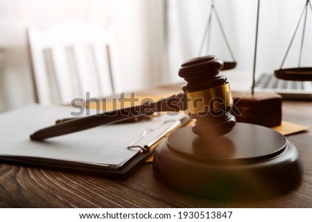Justice and law concept.Male judge in a courtroom with the gavel, working with, computer and docking keyboard, eyeglasses, on table in morning light Royalty-Free Stock Photo #1930513847