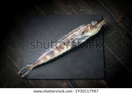 Frozen mackerel icefish on a black stone background. High quality photo