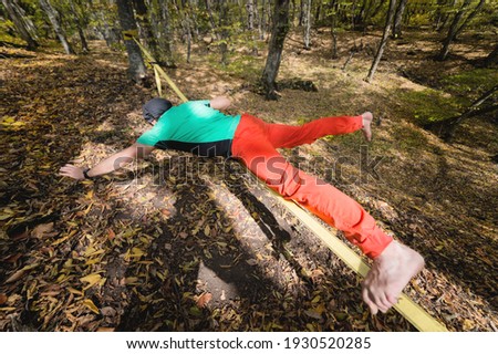 Portrait of a mature male highliner doing slackline balance training in the forest in autumn