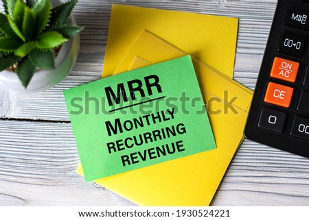 MRR (Monthly Recurring Revenue) - words on green paper on the background of a calculator, and a cactus. Business concept Royalty-Free Stock Photo #1930524221