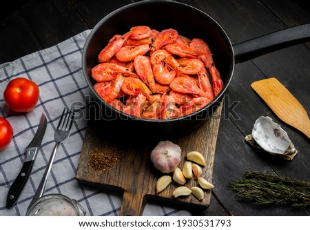 Raw Northern shrimps or prawns with vegetables in a frying pan . Top view