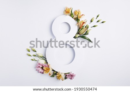 Number 8 with fresh spring flowers with green leaves on bright white background. Minimal Women's day, March 8th or birthday concept. Flat lay, top view.