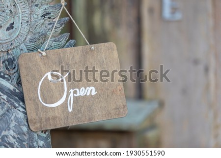The sign has an English letter written "open" and background are blurred.