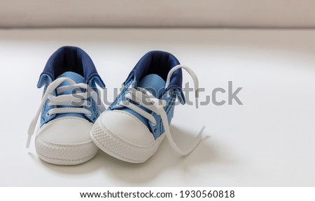 Baby boy sport shoes on white color background. Kid small size blue sneakers, canvas booties closeup view. Space, card invitation template Royalty-Free Stock Photo #1930560818
