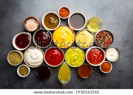 Set of different bowls of various dip sauces, on dark background, top view Royalty-Free Stock Photo #1930563542