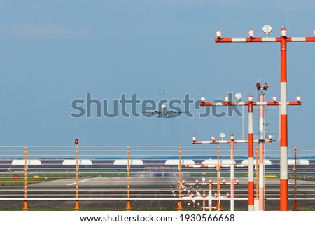 Düsseldorf Airport, Germany: Commercial passenger airplane during takeoff and landing. Landing lights and airport installations in the foreground.  Royalty-Free Stock Photo #1930566668