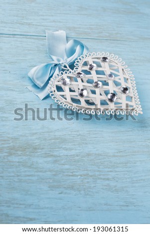 Decorative white heart on blue wooden background, vertical. Selective focus.