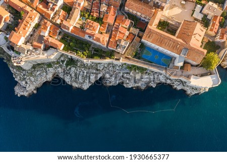 Aerial overhead drone shot of Dubrovnik City Wall by cliff and basketball field in Croatia summer morning