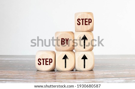 The word step by step on wooden cubes. Achievement or progress in business career. Royalty-Free Stock Photo #1930680587