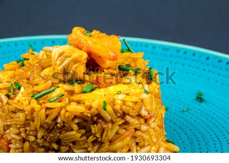 Traditional spanish paella dish with seafood, peas, rice and chicken over grunge blue background. Top view. Selective focus