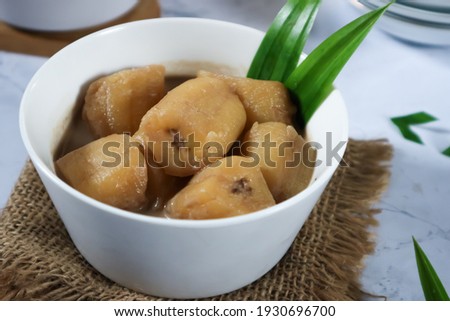Unfocus picture of bowl of Kolak pisang, Indonesian dessert, made from kepok banana cooked with palm sugar, coconut milk, pandanus leaves on white background. Very popular during Ramadhan. Isolated
