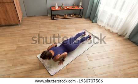 Top view of young woman in bodysuit exercising, doing Four Limbed Staff yoga pose on a mat in living room at home on a daytime. Fitness, relaxation, stay home concept. Web Banner