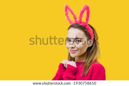 young woman in bunny ears on a yellow background