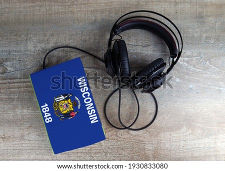 Headphones and book. The book has a cover in the form of Wisconsin flag. Concept audiobooks. Learning languages.