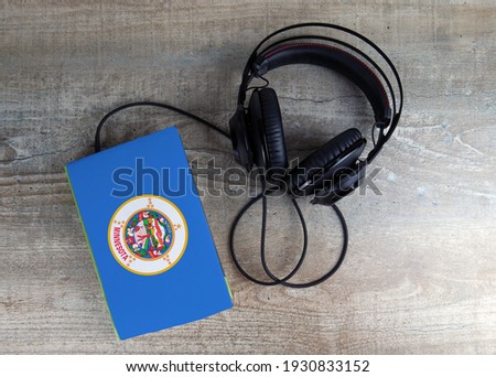 Headphones and book. The book has a cover in the form of Minnesota flag. Concept audiobooks. Learning languages.