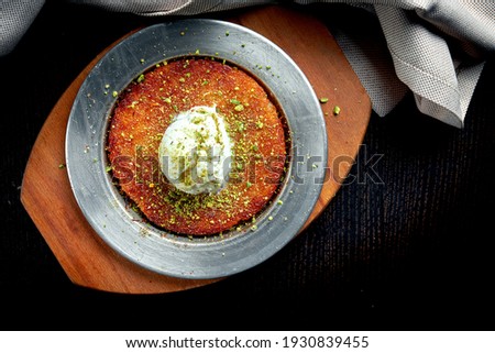 Appetizing Turkish sweetness Kanafeh made with shredded filo pastry with honey, pistachios and white ice cream Royalty-Free Stock Photo #1930839455
