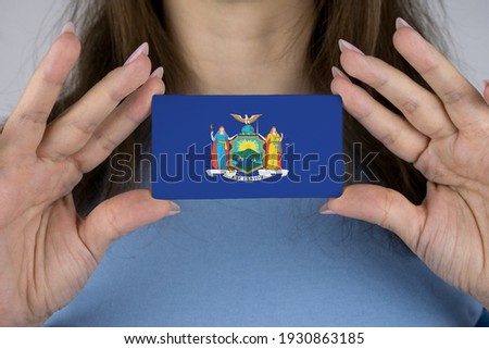 A woman shows a business card with an image of the New York flag