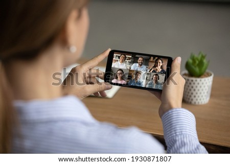Close up back view of woman have webcam online team meeting with diverse colleagues on smartphone. Female talk speak on video call with multiracial businesspeople on cellphone. Virtual event concept. Royalty-Free Stock Photo #1930871807
