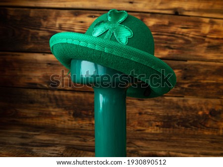 Heavy green dumbbell wearing a hat with shamrock leaf clover for St. Patrick's Day. Healthy fitness gym composition concept, with copyspace on wooden background.