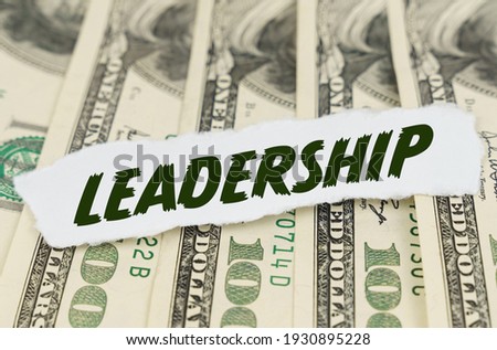 Business and finance concept. On the background of dollars lies a piece of paper with the text - LEADERSHIP
