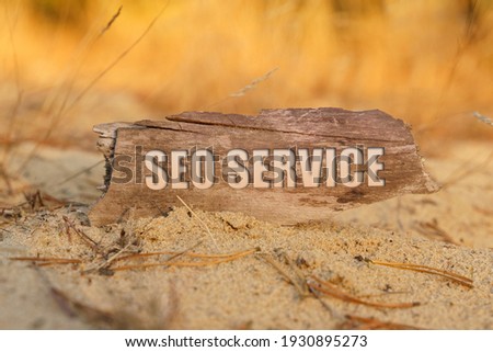 Business and technology concept. On the sand against a background of yellow grass, a signboard with the inscription - SEO SERVICE
