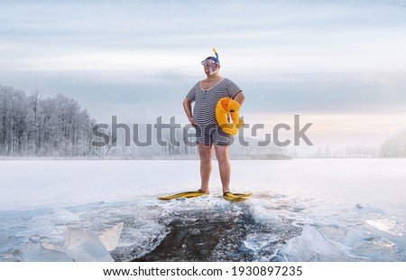 Fuunny overweight, retro swimmer standing by the ice hole in the lake, at the cold sunrise with copy space  Royalty-Free Stock Photo #1930897235