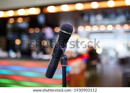 Close-up of microphone on stand against colorful blurred interior background