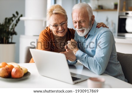 Embraced mature couple surfing the Internet on laptop at home Royalty-Free Stock Photo #1930917869