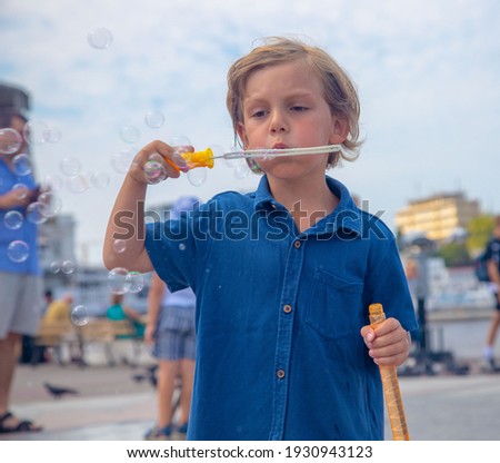 a five-year-old boy in a blue shirt blows soap bubbles