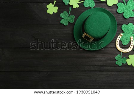 Leprechaun's hat and St. Patrick's day decor on black wooden background, flat lay. Space for text
