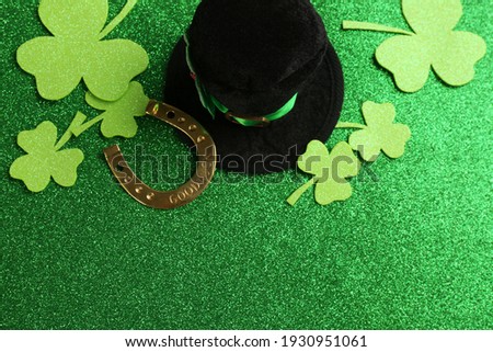 Flat lay composition with leprechaun hat on green glitter background, space for text. St Patrick's Day celebration