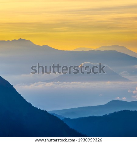 Beautiful landscape of blue and golden ( yellow) moment mountains layers during sunrise located st Bromo indonesia. soft and grain effect
