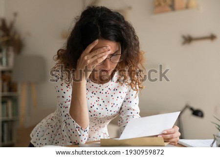 Bad news. Confused young female wearing glasses open mortgage loan rejection letter official refusal from bank credit organization. Upset woman small business owner get paper notice about tax debt Royalty-Free Stock Photo #1930959872